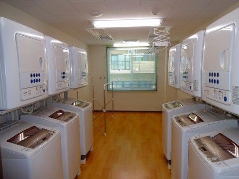窓がある洗濯室は、床がフローリングでゆとりあるスペースに、洗濯機と乾燥機を各６台設置。車椅子をご利用の方でも使いやすい環境を整えている。