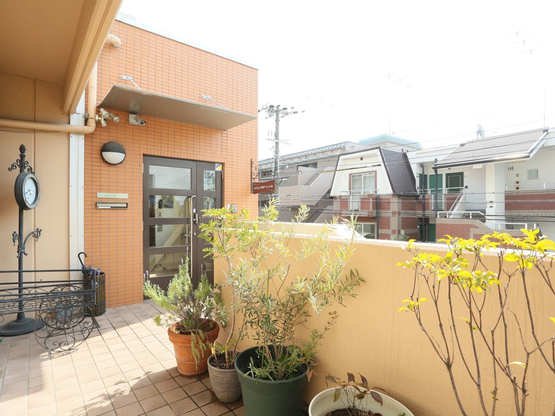 入口は２階にあり、入口前にはさまざまな観葉植物が置かれている。１階に入口がないため、プライバシーを守り、安心して生活できる環境である。