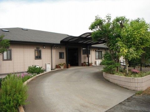 玄関は緩やかなアーチ型の屋根が設置されており、両サイドには色とりどりの花が植えられた木製の花壇が設置されている。