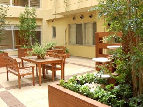 木製のテーブルセットや花壇などが、いくつも配置されている屋外デッキ