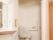 白を基調としたトイレスペースは清潔感に溢れている。壁にエル型の手すり、ナースコール、トイレットペーパーホルダーを備えている。