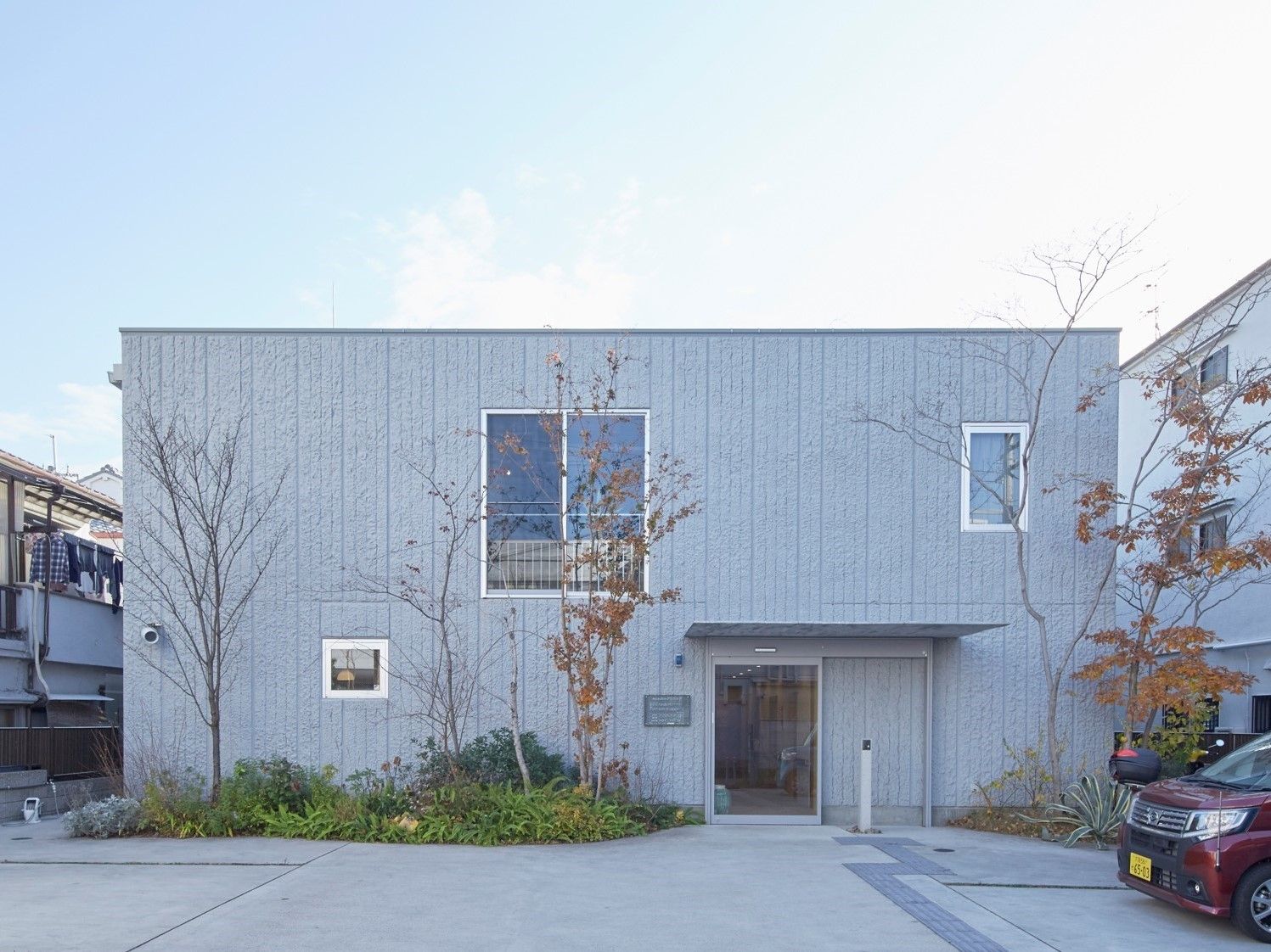 グレーの２階建ての建物である。大小の窓があり、おしゃれな造りとなっている。建物前には木々が植えられている。