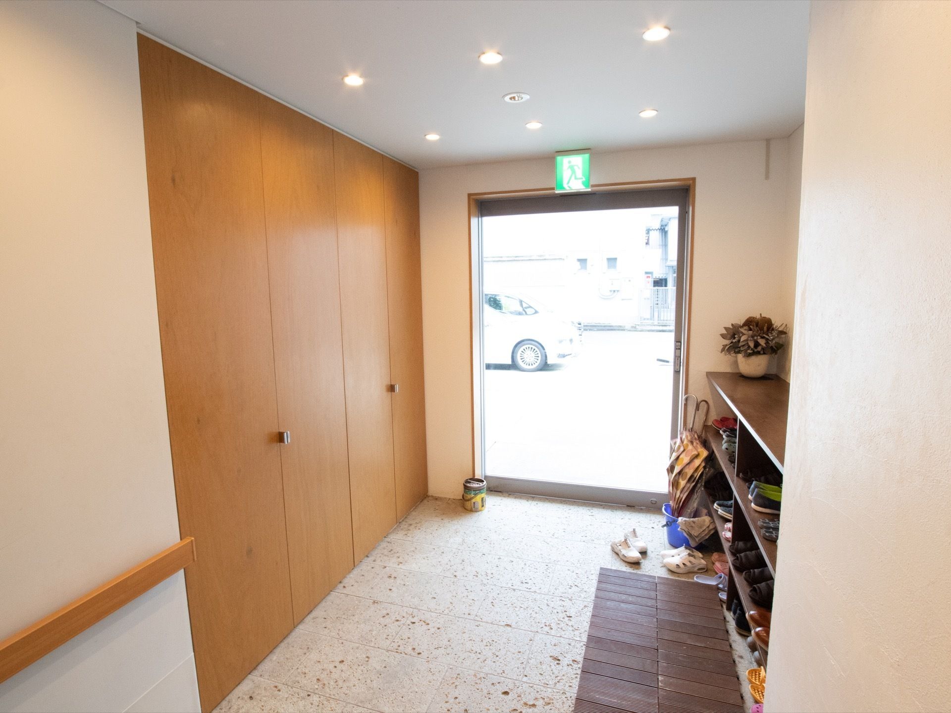 玄関は大きなガラスがあり、明るい。３段の下駄箱があり、入居者様の靴を収納している。館内の壁には手すりが取りつけられている。