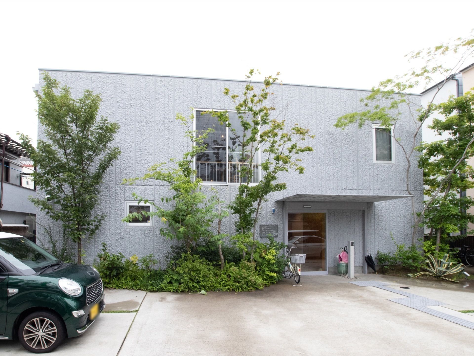 施設はグレーの外壁の建物である。玄関の前のスペースには屋根があるので、雨の日も濡れることなく施設に入ることができる。
