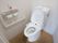 トイレの便器には、温水洗浄便座や手洗いタンクが設置されている。呼出ボタンとＬ型手すりが壁に備えつけられている。