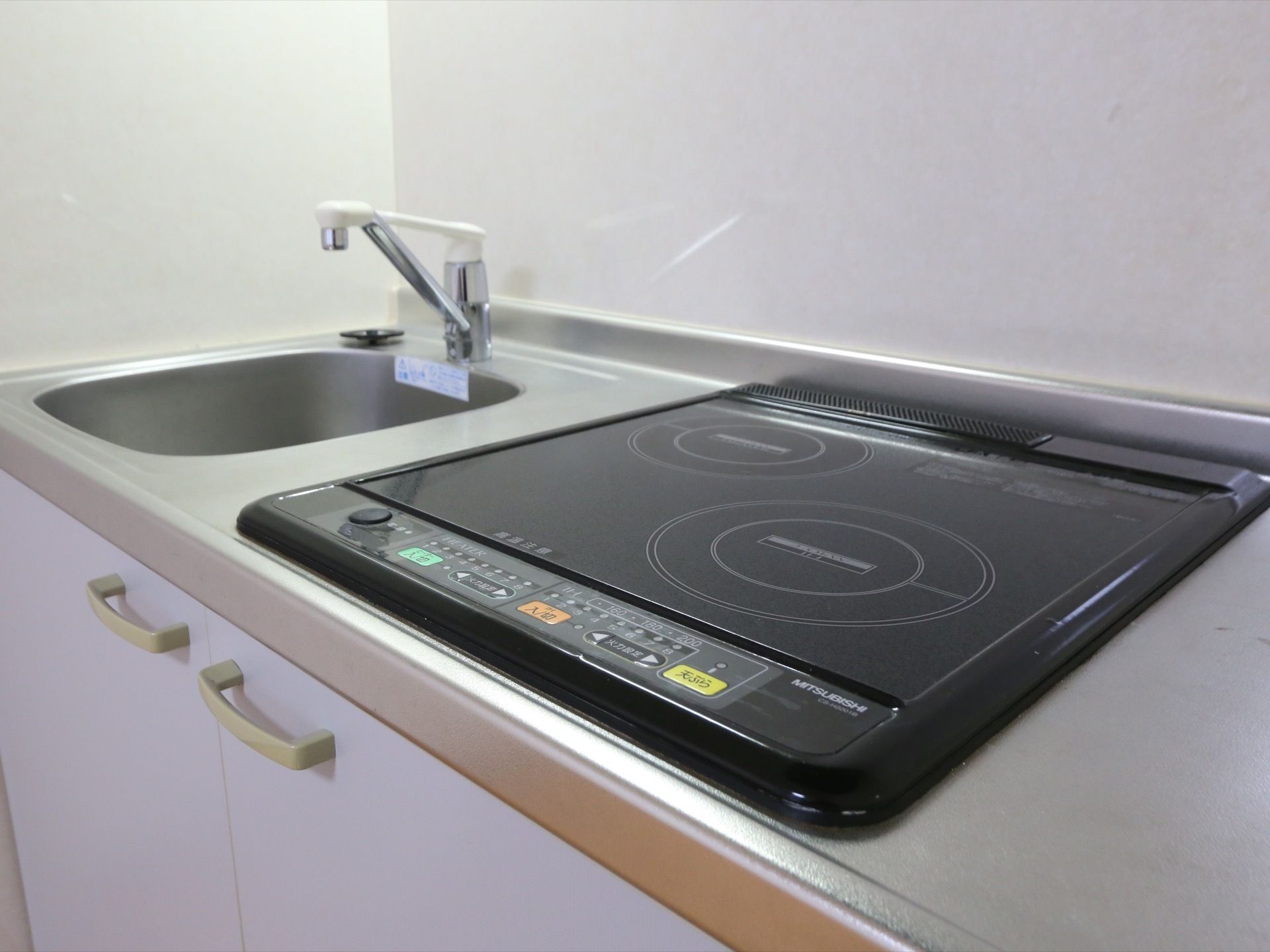 居室にあるミニキッチン。流し台の横には電熱ヒーターが設置されている。コンロ部分が２つ付いている。流し台の下は収納スペースになっている。
