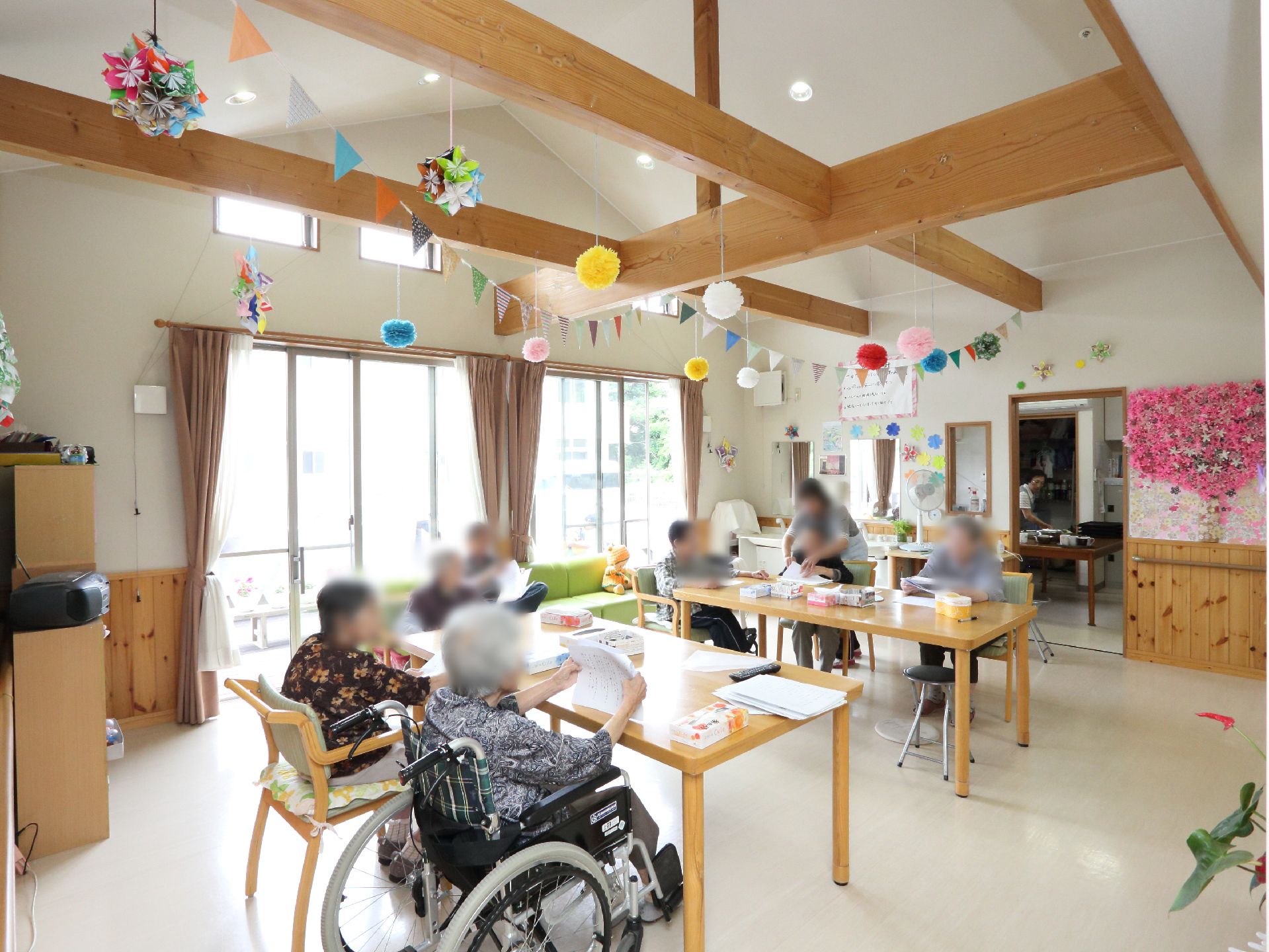 リビングは天井が広く開放的な作り。窓も大きく外から光がよく入る。テーブルは2つでスペースが広く車椅子で利用できる。