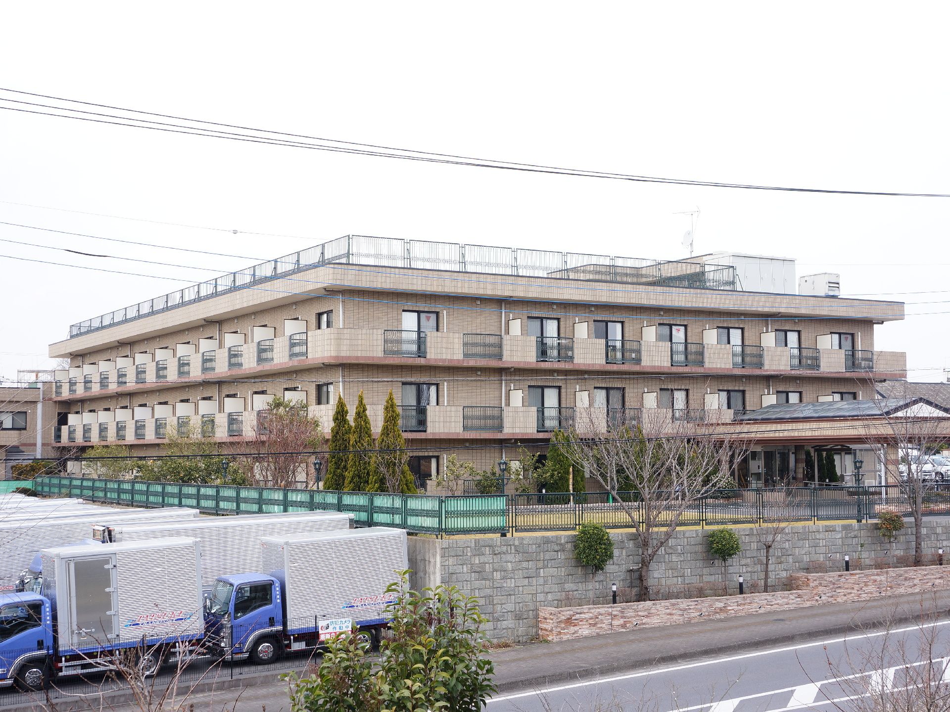 3階建ての立派な建物である。道路よりも少し上に建っている。屋上には柵もついている。アイボリー系やブラウン系を基調とした外観である。