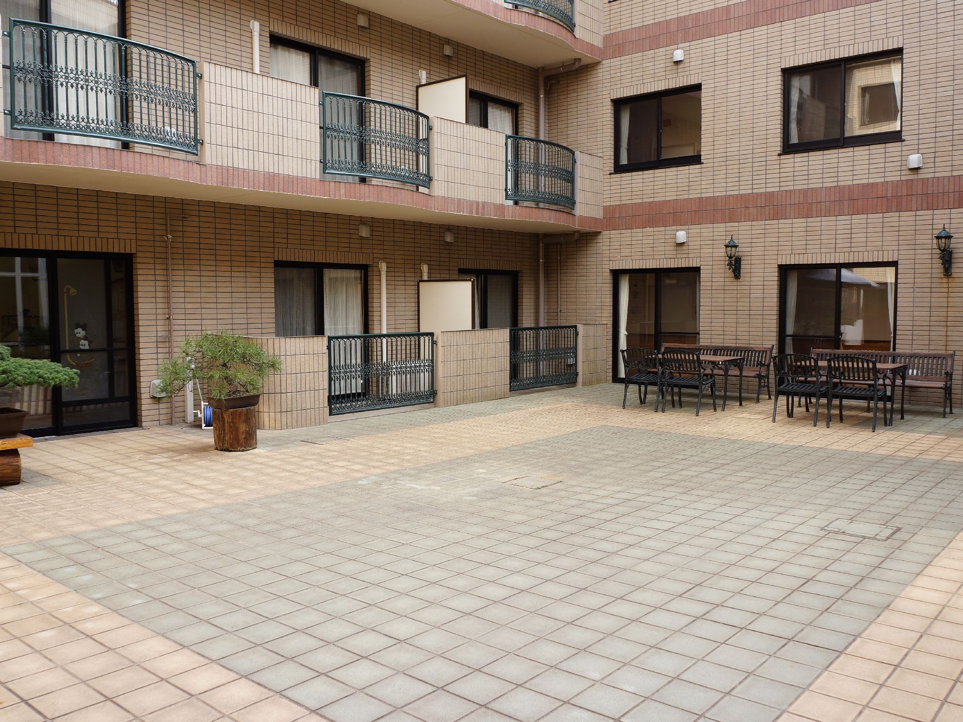 ベンチや長いテーブルがある中庭である。出入り口には、大きな松の盆栽がある。各部屋から、中庭を望むことができる。