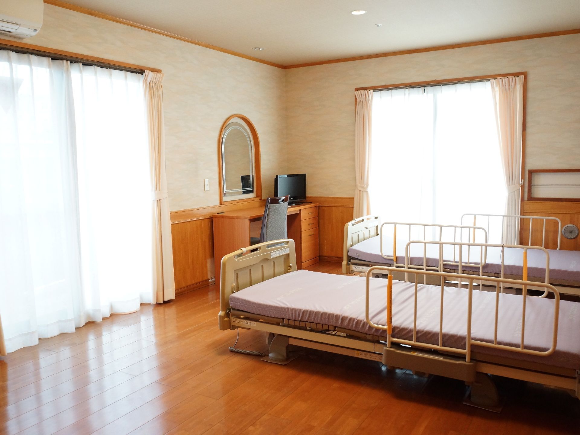 ２か所の窓から陽光が差し込む二人用居室には、デスクとテレビ、そして鏡が設置されており、ドレッサーとしても使用できる。