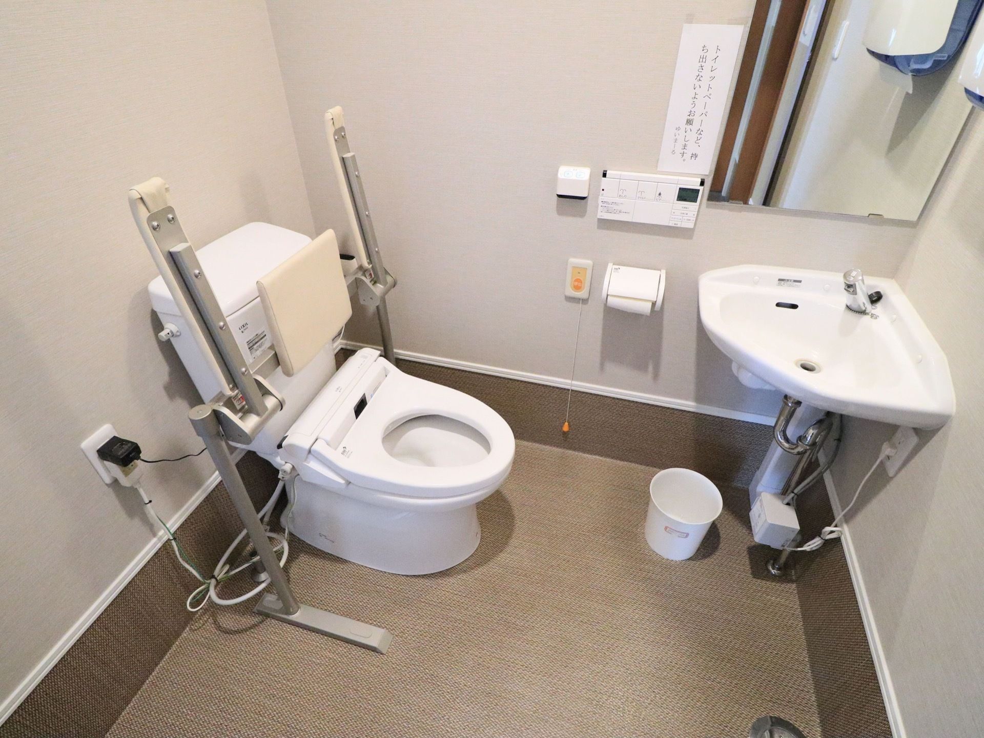 手洗い場のついたトイレには温水洗浄便座器が完備され、背もたれパッド付きの可動式手すりが設置されている。