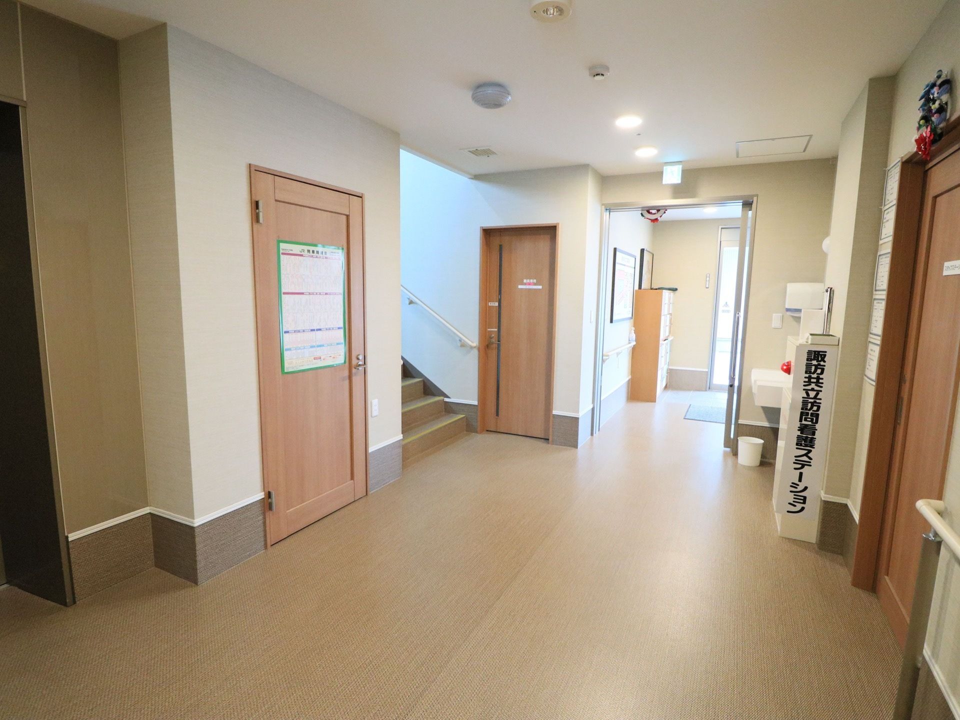 施設内の廊下である。壁に手すりが取りつけられた階段が完備されている。洗面台や消火設備が整えられている。