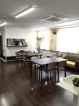 シックな色合いのテーブルが配置されており、落ち着いた空間になっている。部屋の隅には洗面台があり鉢植えが置かれている。