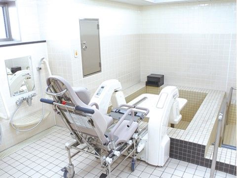 大きな可動椅子に乗ったまま浴槽に入ることができる介護設備を備えた浴室