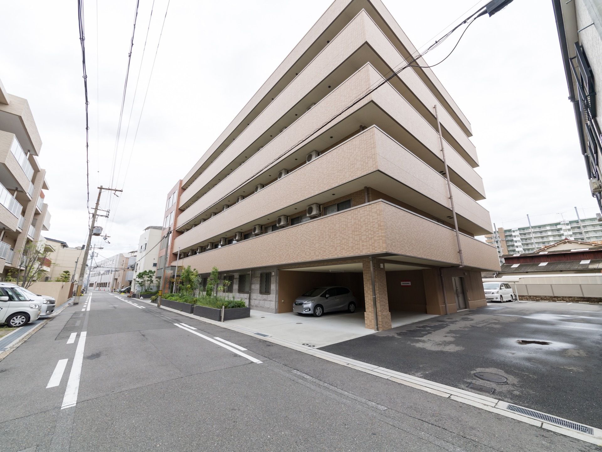 建物の１階部分には空洞を設け、１～２台の車を停める事ができる。建物横には、アスファルトの通路があり、奥に駐車場がある。