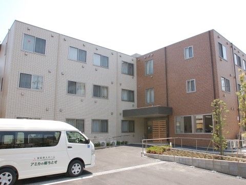 玄関前のスペースに施設保有の車が停まっている施設外観