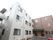 3階建ての建物。外壁は、白色と茶色からなる。エントランスは茶色の自動ドアになっている。建物の脇には、木花が植えられている。