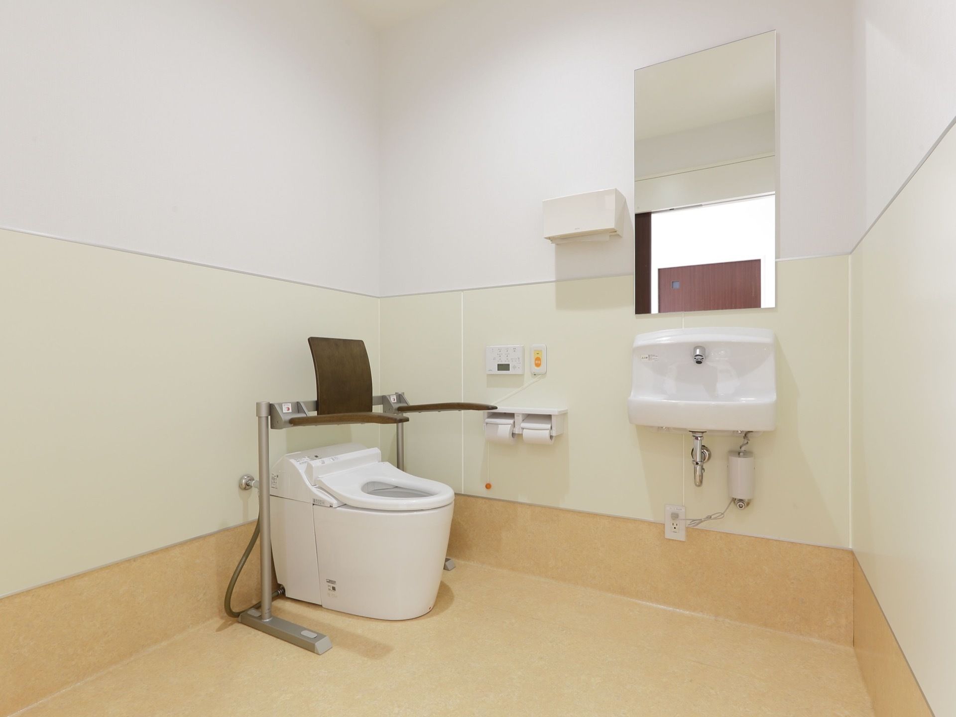 広々としたスペースが確保されているトイレである。右端には、大きな鏡の付いた手洗い器が取り付けられている。
