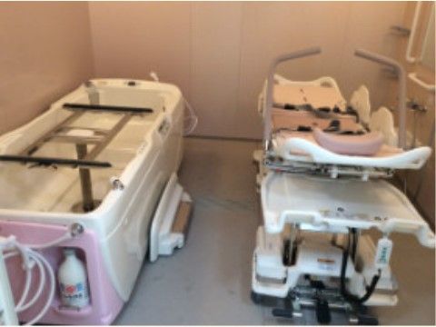 可動式のベッドタイプの入浴設備が浴槽の隣に置かれている介護浴室