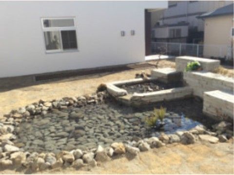 ホームの外壁は白を基調としている。石が敷き詰められた池の横には、レンガが積まれた壁が設置されている。