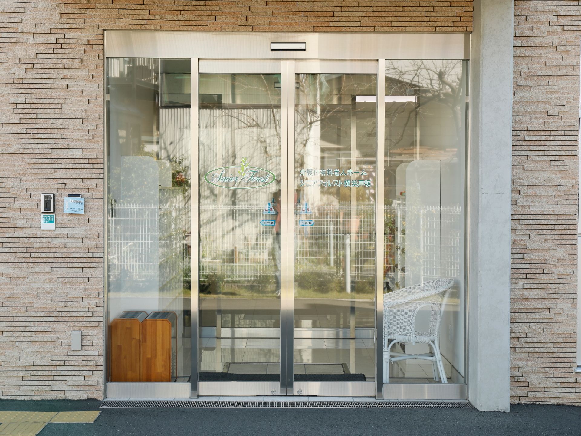 玄関は自動ドアを設けており、ドアのガラスには施設名が記されている。ドアの横の外壁にはインターホンが備わっている。