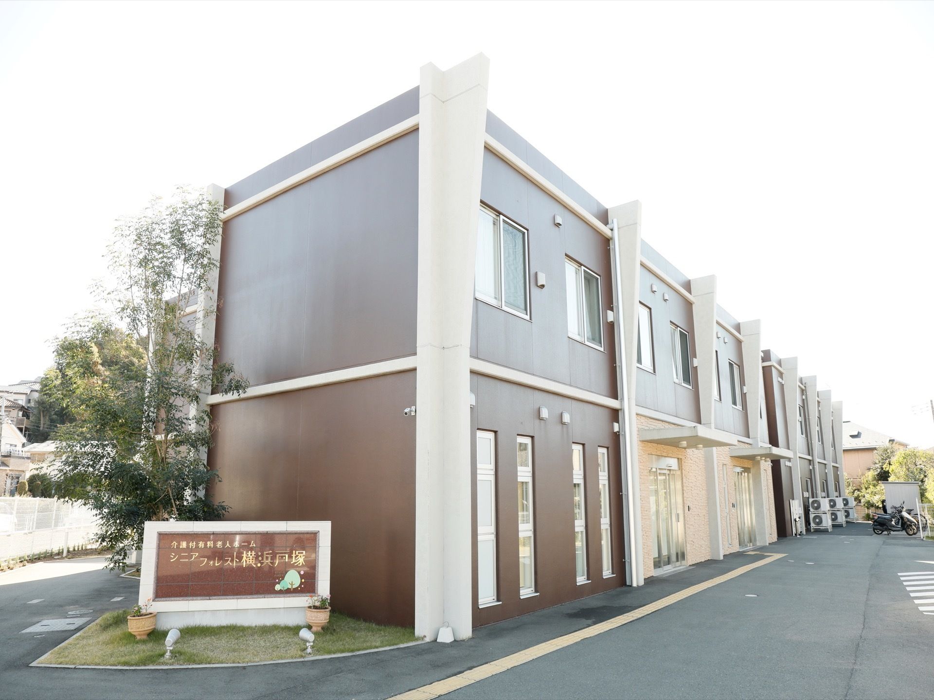 2階建ての施設の建物は濃い茶色を基調とした外観である。建物の横には施設名を記した看板が設けられている。