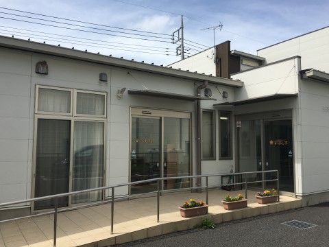 手すりの付いたゆるやかなスロープがあり、プランターが置かれている玄関付近