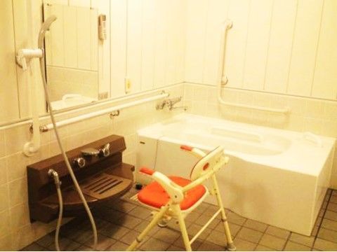 ひじ掛けや背もたれのついた椅子が洗い場に置かれている浴室