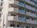 ベージュの壁が特徴的な大きなマンションのような建物になっている。各部屋にベランダがついていることがわかる。