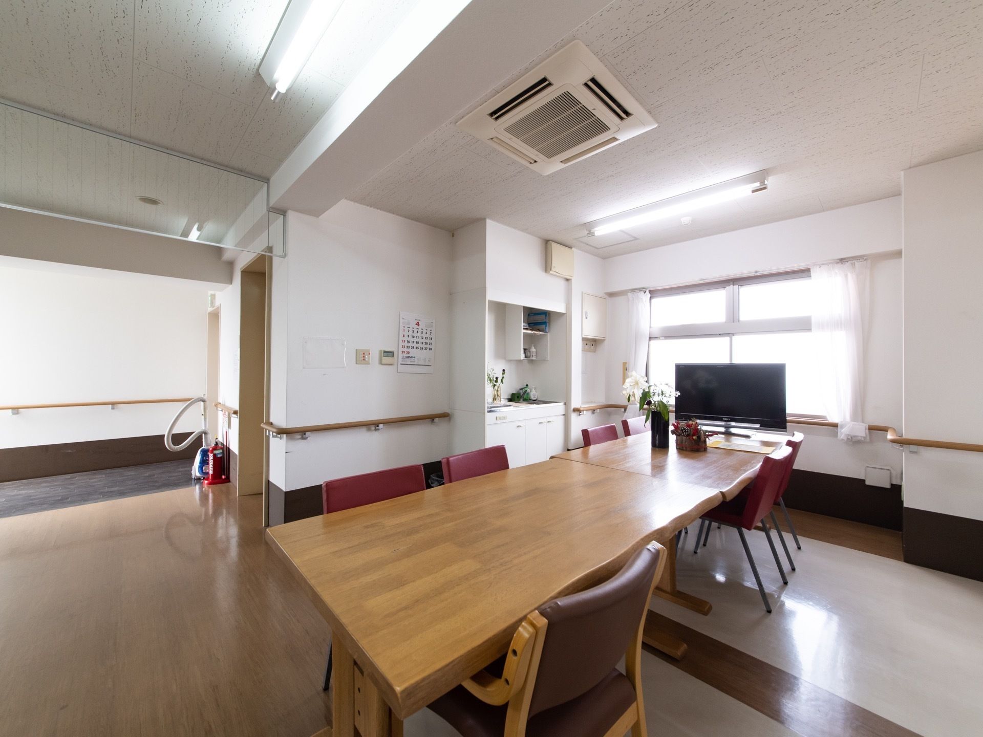 リビングスペースの中央には木製の大きなテーブルが設置されており、奥には大型のワイドテレビが置かれている。