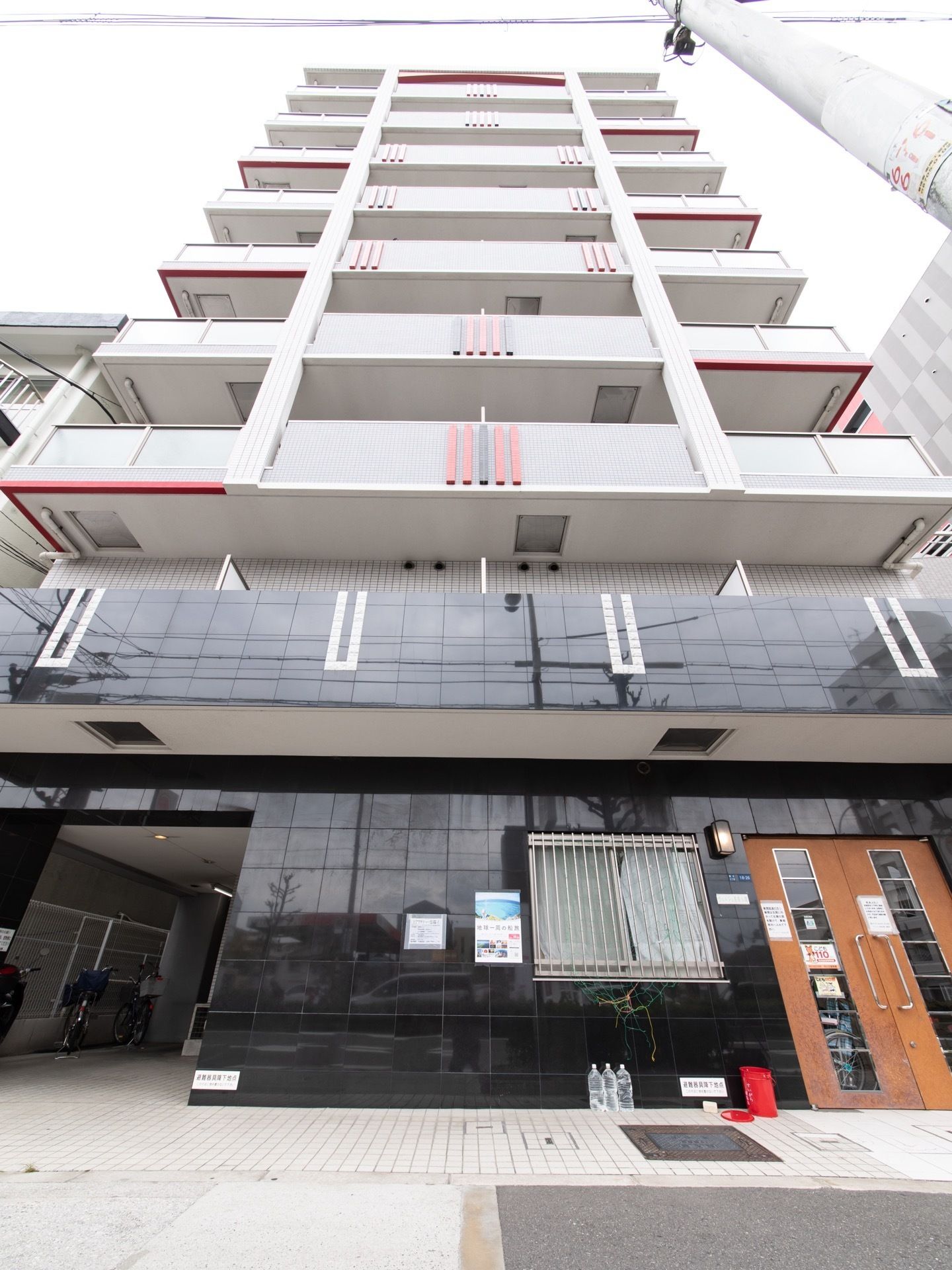 マンションビル風の外観をした施設建物。一階部分の外壁には、黒く光沢のある材質の化粧パネルが貼られている。