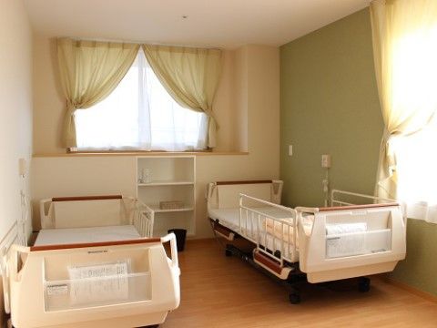 窓が2ヶ所に設置され、2台の介護用ベッドが置かれている居室