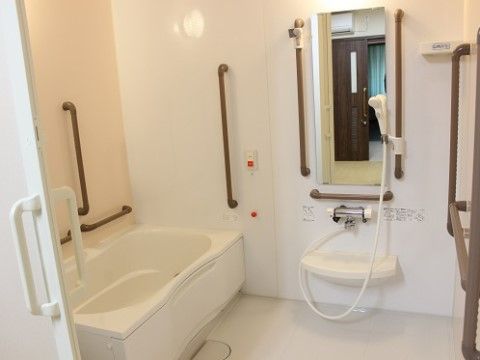 白い壁に手すりや緊急呼び出しブザーが設置されている個浴室