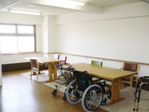 白い壁伝いに手すりが設置され、テーブルセットが配置されている共有スペース