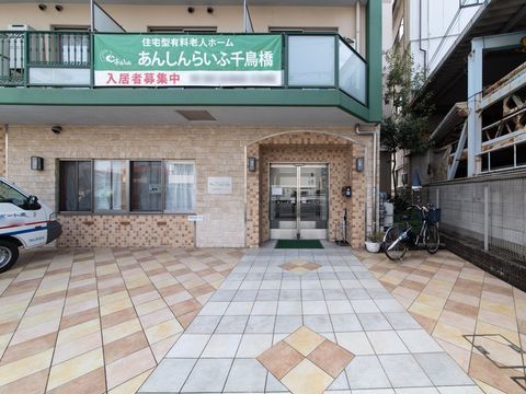 玄関上のバルコニーに入居者様募集の幕が掲出されている施設外観