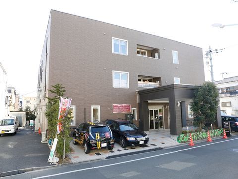 車寄せがあり、その横に2台の車が停められている玄関前