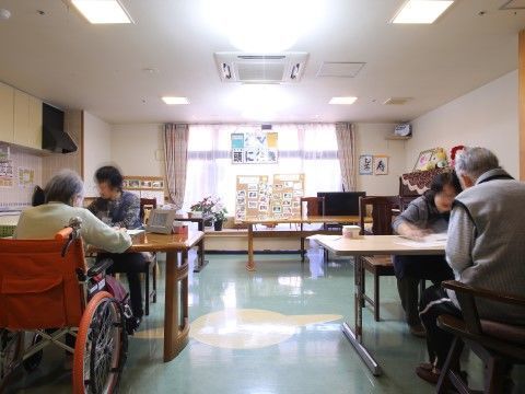 テーブルを挟んで入居者様が座っている、広さのある休憩スペース