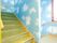 階段は下が緑色に、壁には空が描かれているため、利用者の方が階段の上り下りを楽しめるように工夫されている。また、手すりが設置されている。