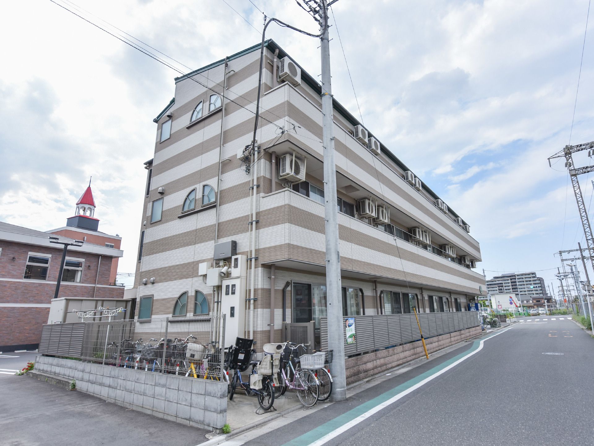 建物の外装は白と茶色のボーダー柄となっている。建物の1階部分は外の道路から見えないようフェンスで仕切られている。