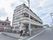 建物の外装は白と茶色のボーダー柄となっている。建物の1階部分は外の道路から見えないようフェンスで仕切られている。
