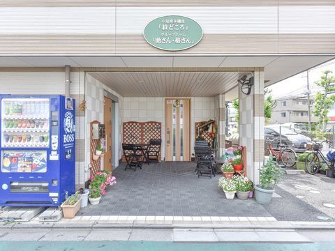 飲料の自動販売機の右側の奥まった所にある開き戸タイプの玄関