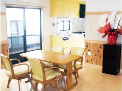 座面が回るタイプの椅子が置かれ、壁の近くに花が飾られている食堂