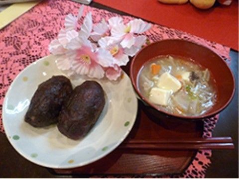 ピンク色のランチョンマットの上に置かれたおはぎと味噌汁
