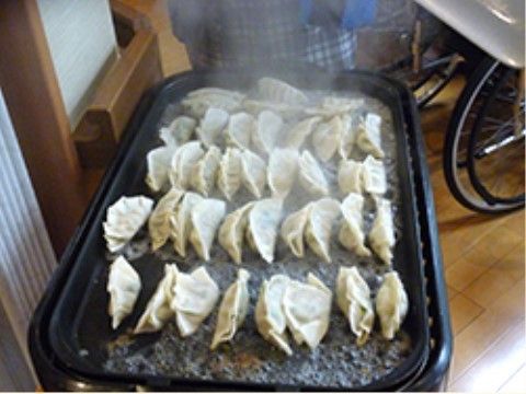 ホットプレートの上で焼き上げられているたくさんの餃子