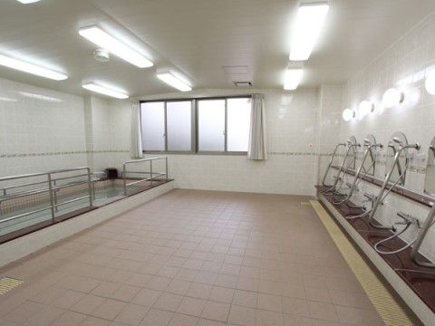 大きな浴槽と複数のシャワーが設置された大浴場