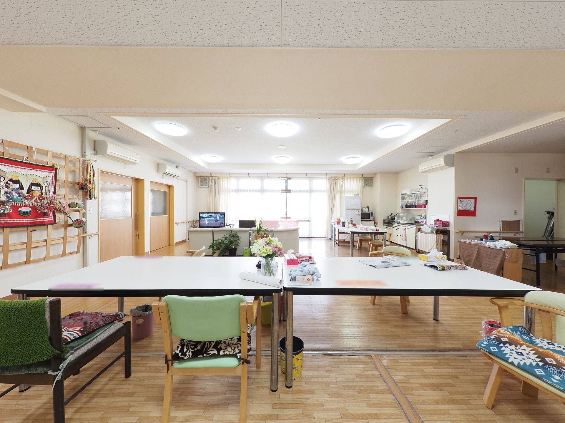 広さのある部屋にテーブル、椅子、ソファなどが置かれており、キッチンや冷蔵庫が完備されている。天井にはシーリングライトが６つ設置されている。