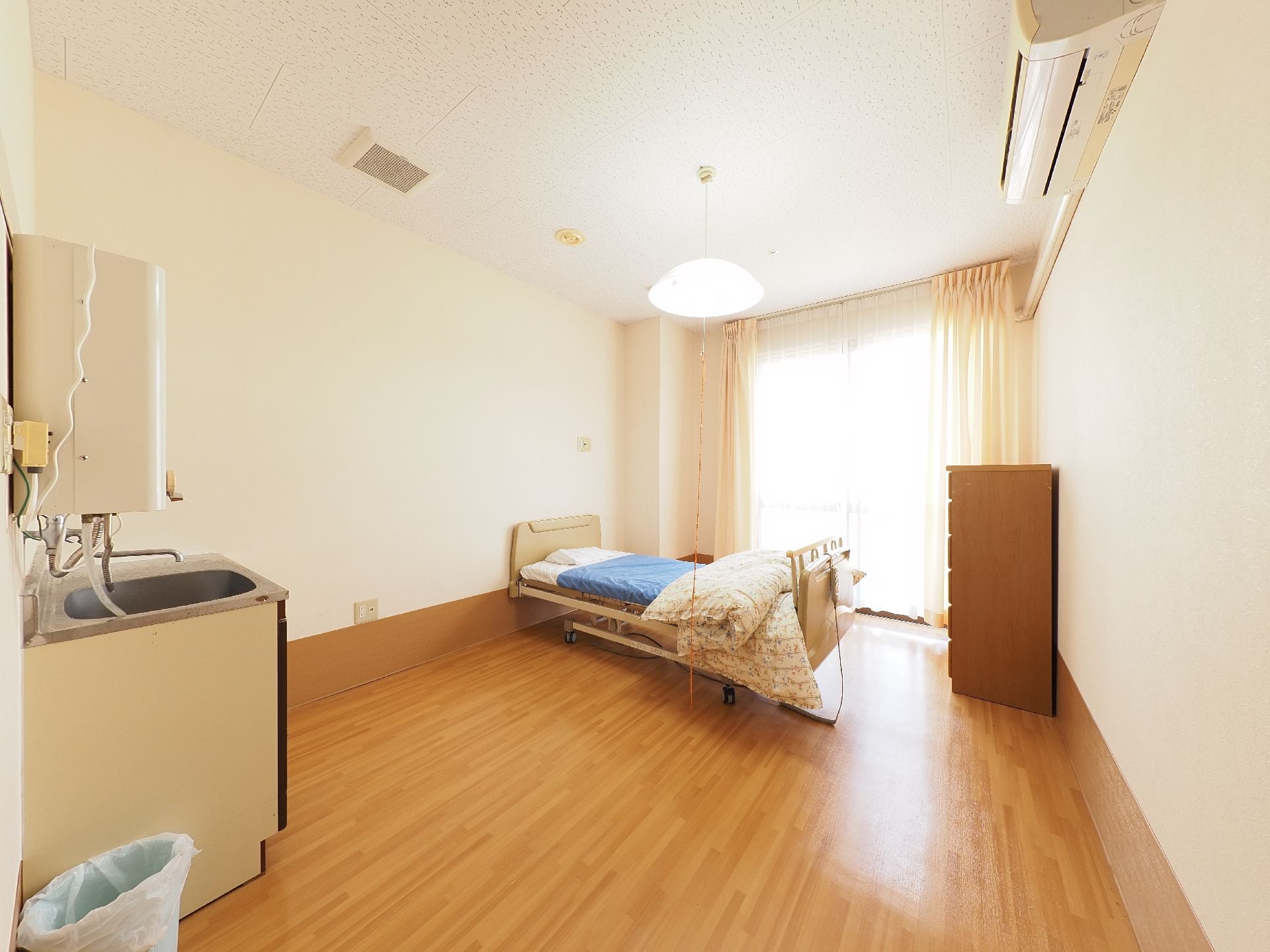 湯沸し器のついた洗面台と介護ベッドが設置されている居室