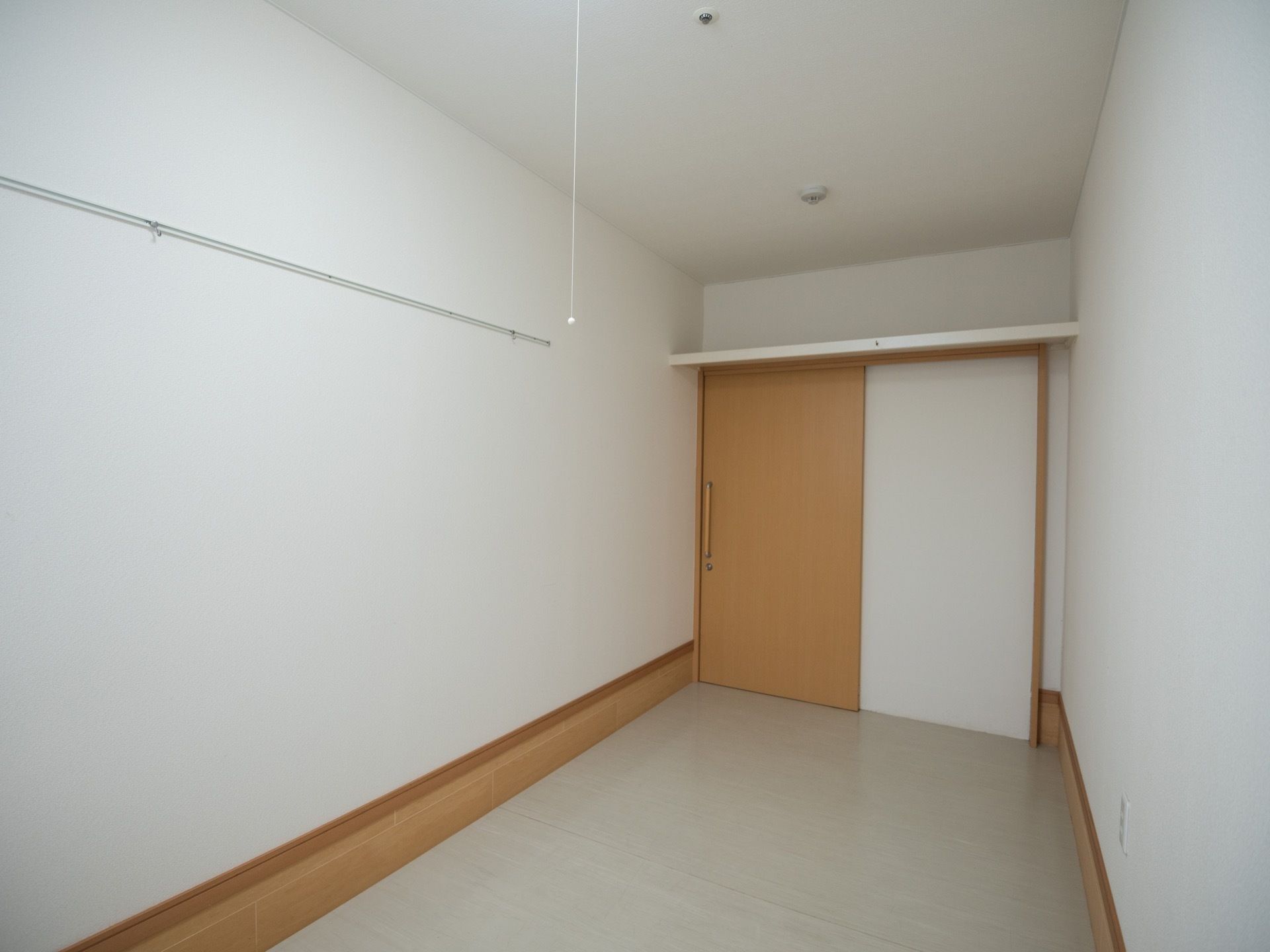 居室のドアの上に作りつけの棚が設置されている。壁にはピクチャーレールが取りつけられ、ジャケットなどの軽い物を吊るせるようになっている。
