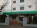 施設は白壁に玄関の屋根は緑色に塗装されている。屋根には施設名が大きく記載されている。敷地の外周は塀とフェンスが設けられている。