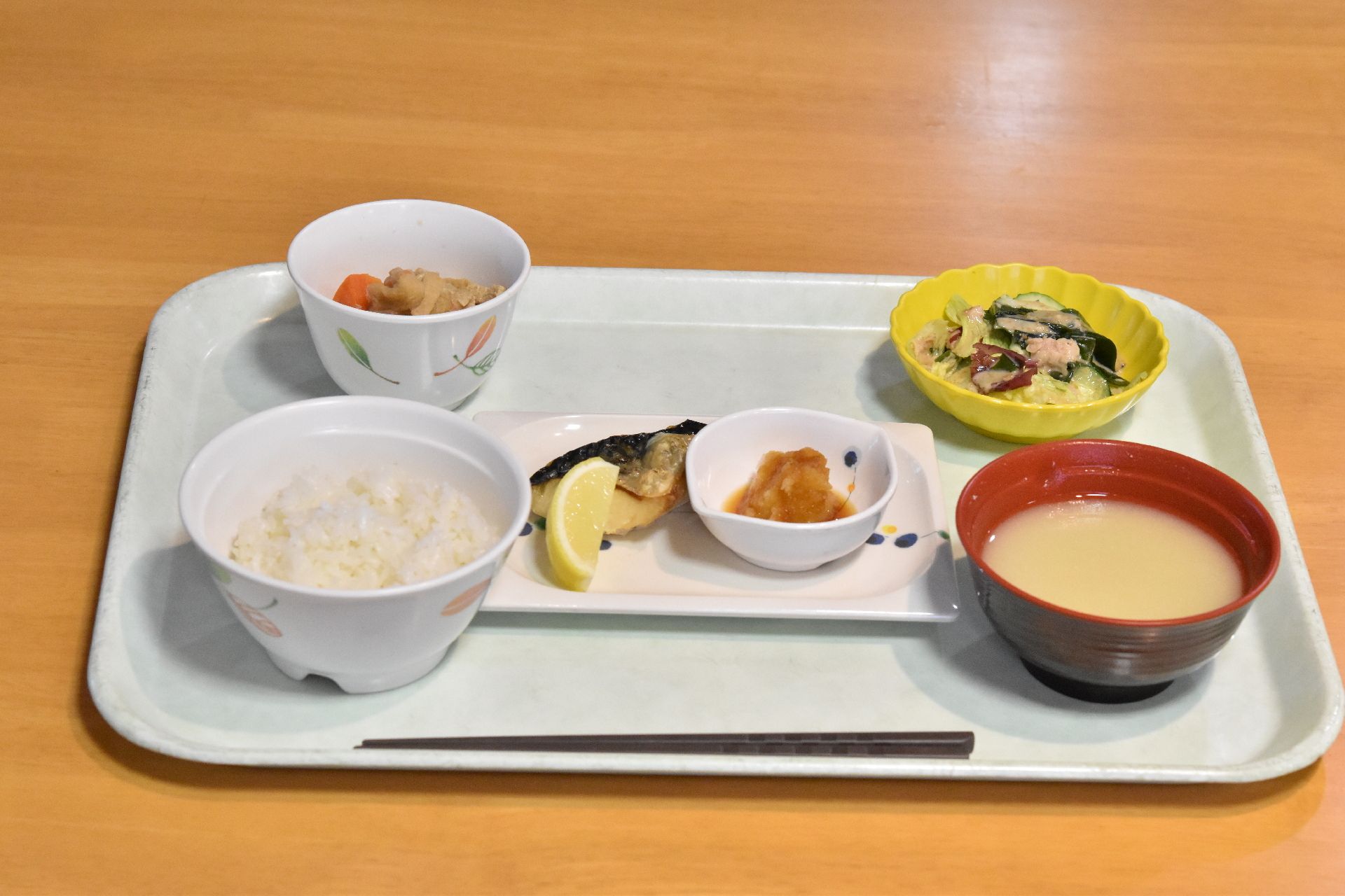 中央に主菜のお皿があり、その手前に白いご飯とみそ汁が置かれているお食事